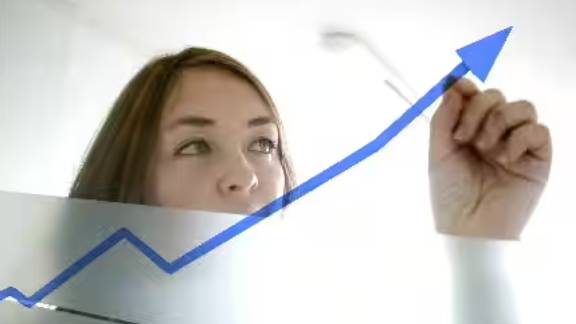 A woman tracing an upward arrow on a glass door with a marker