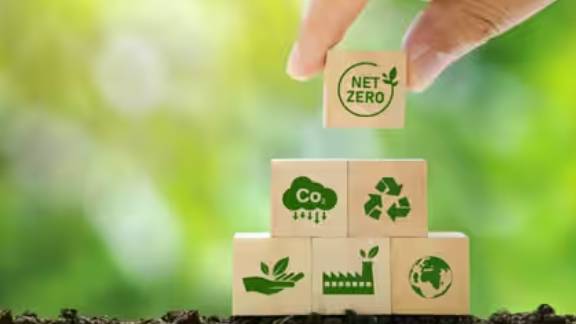 Close-up of a person placing a wooden block onto a set of wooden blocks, each with a symbol depicting sustainability