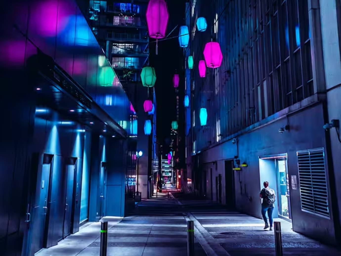 An urban alleyway lined with sidewalks lit up at night