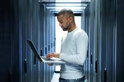 A man working on a laptop in a data centre