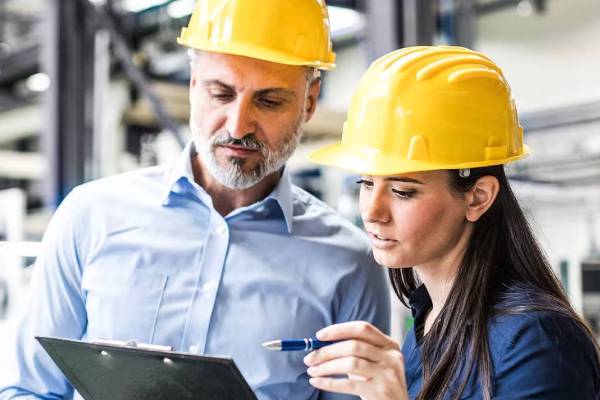 Two engineers reading a document on a writing pad 