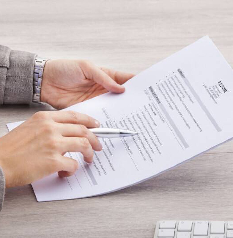 businesswoman at desk holding resume