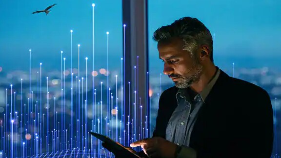 A businessman scrolling on a tablet near a window in an office