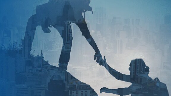 A hiker helping a fellow hiker climb up a hill