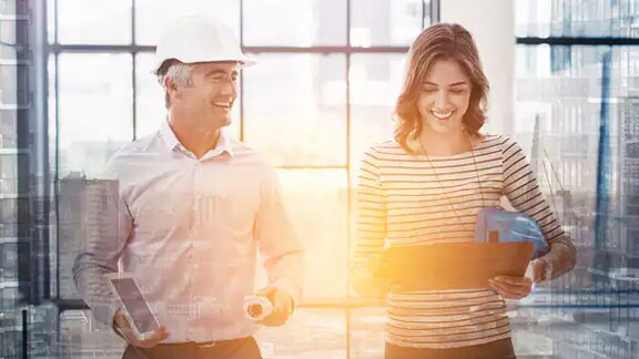 A male mechanic smiling near a female mechanic holding a tablet
