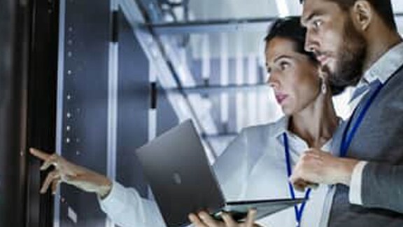 Two people using a laptop in a data centre
