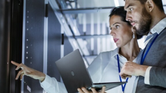 two people using a laptop in a data centre 