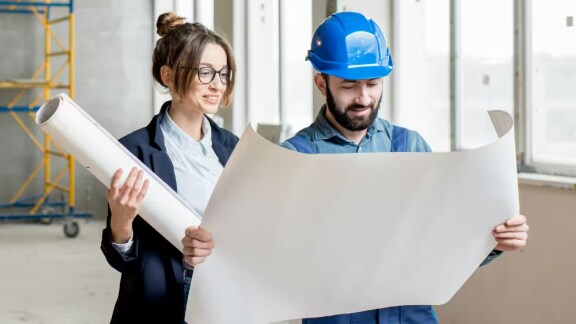 man and woman looking at a chart in a construction site