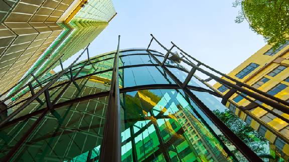Frog's-eye view of corporate buildings and trees against a clear daytime sky