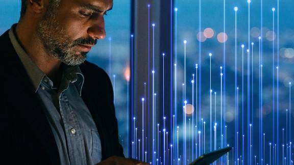 A man scrolling on a tablet near a window, overlaid with OpenBlue graphics
