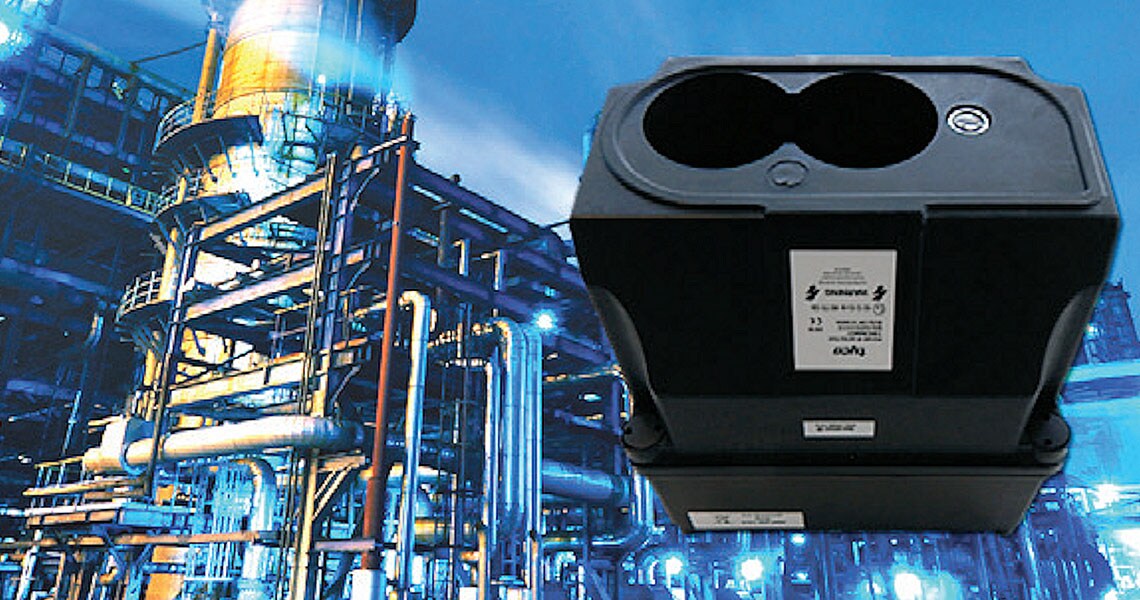 A black oil mist detector with an oil rig in the background