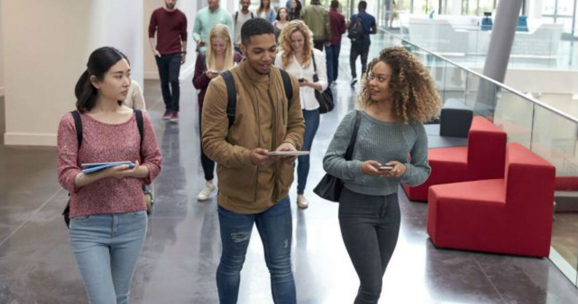Students walking in a college hallway with glass railings on the side