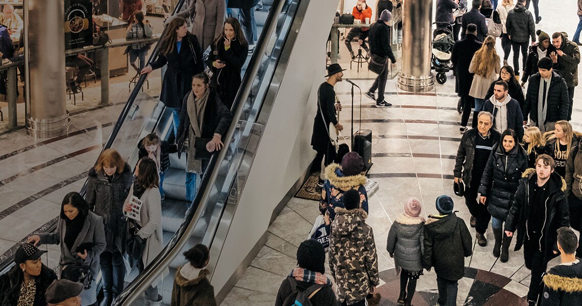 A crowded shopping complex with an escalator