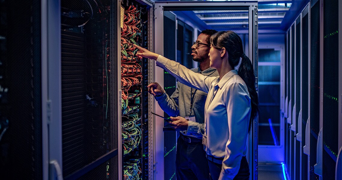 Two people in front of a data centre rack