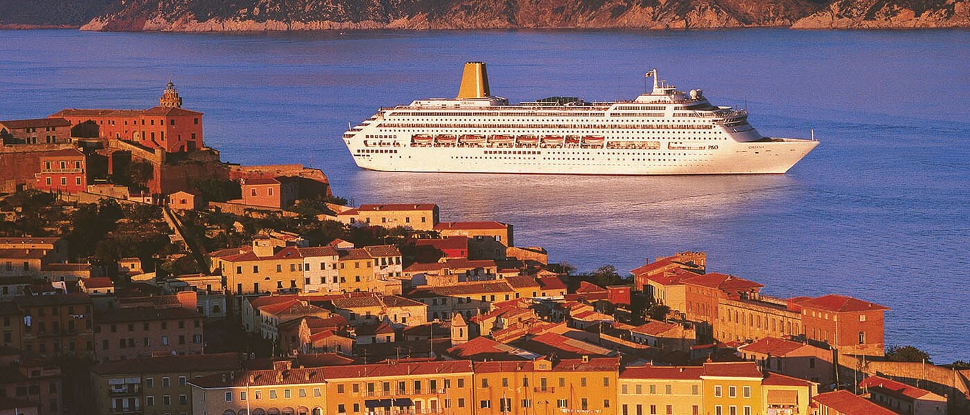 A bird's eye view of a city and the ocean with a ship sailing