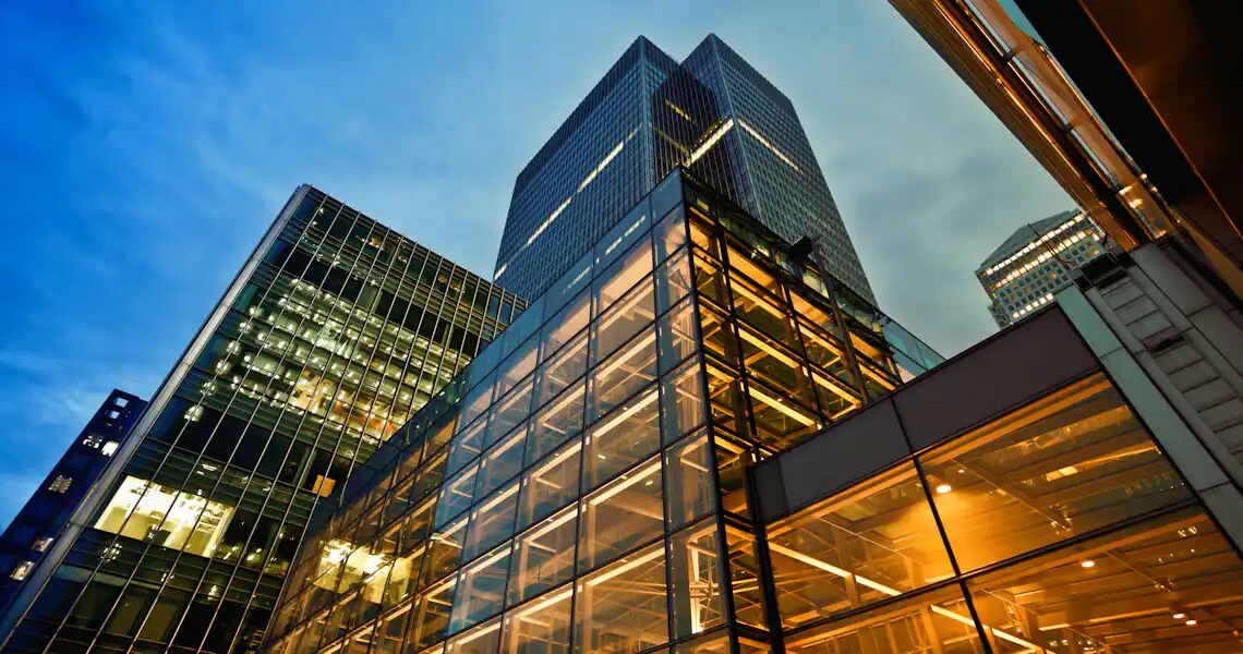 Upshot of glass buildings with the lights on at dusk