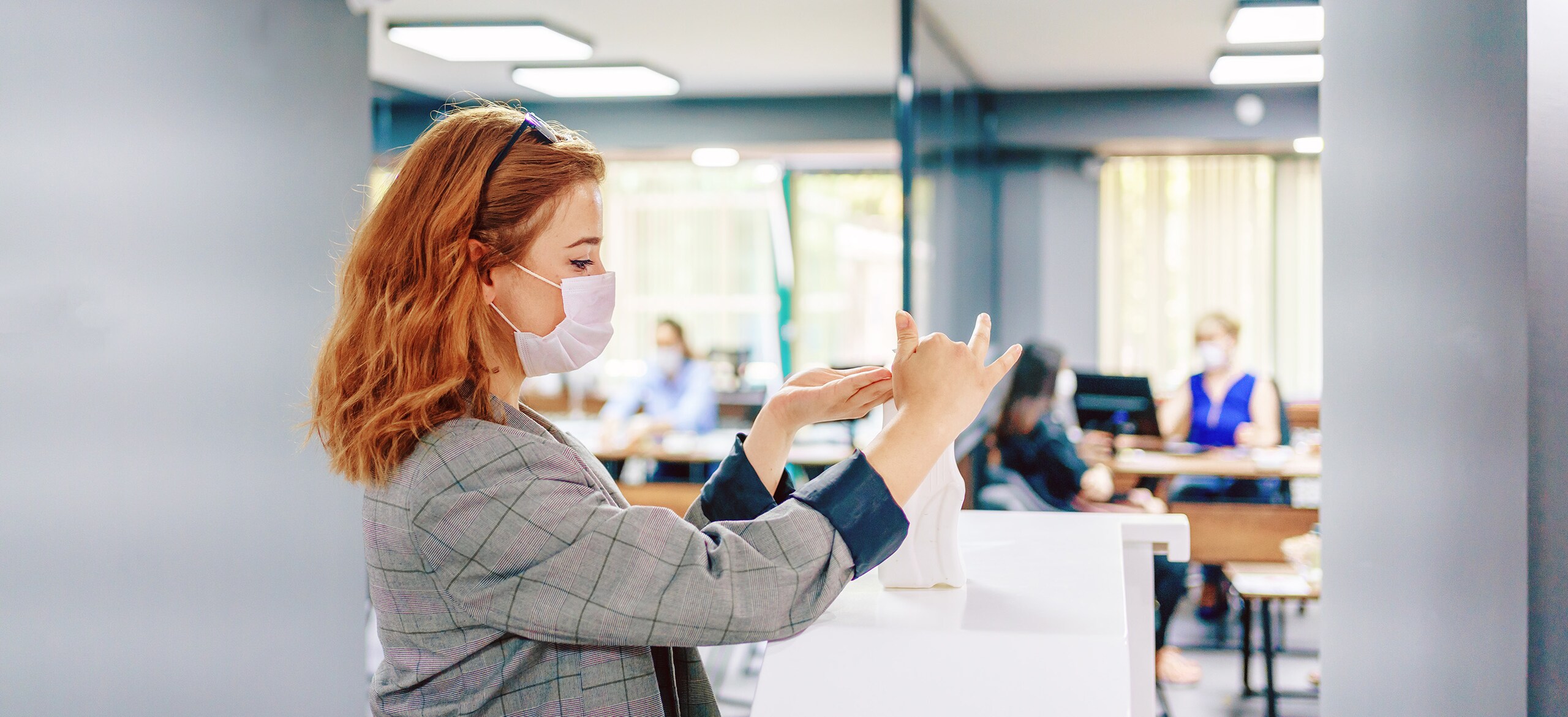A woman in a surgical mask working with a bottle on a desk