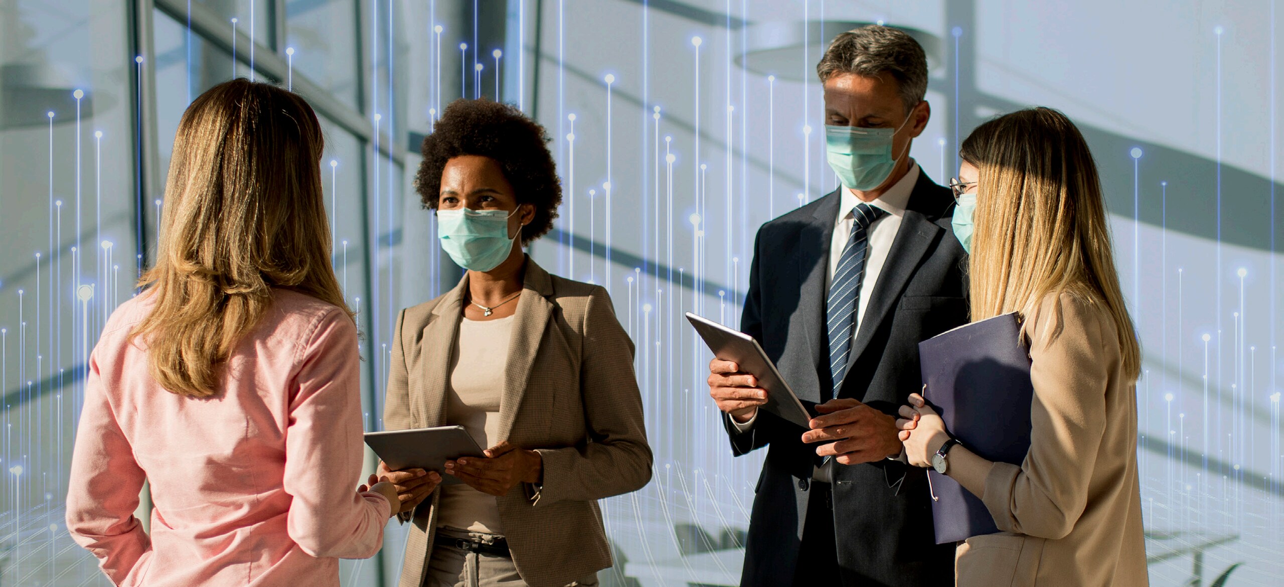 Two business people with tablets talking to two others