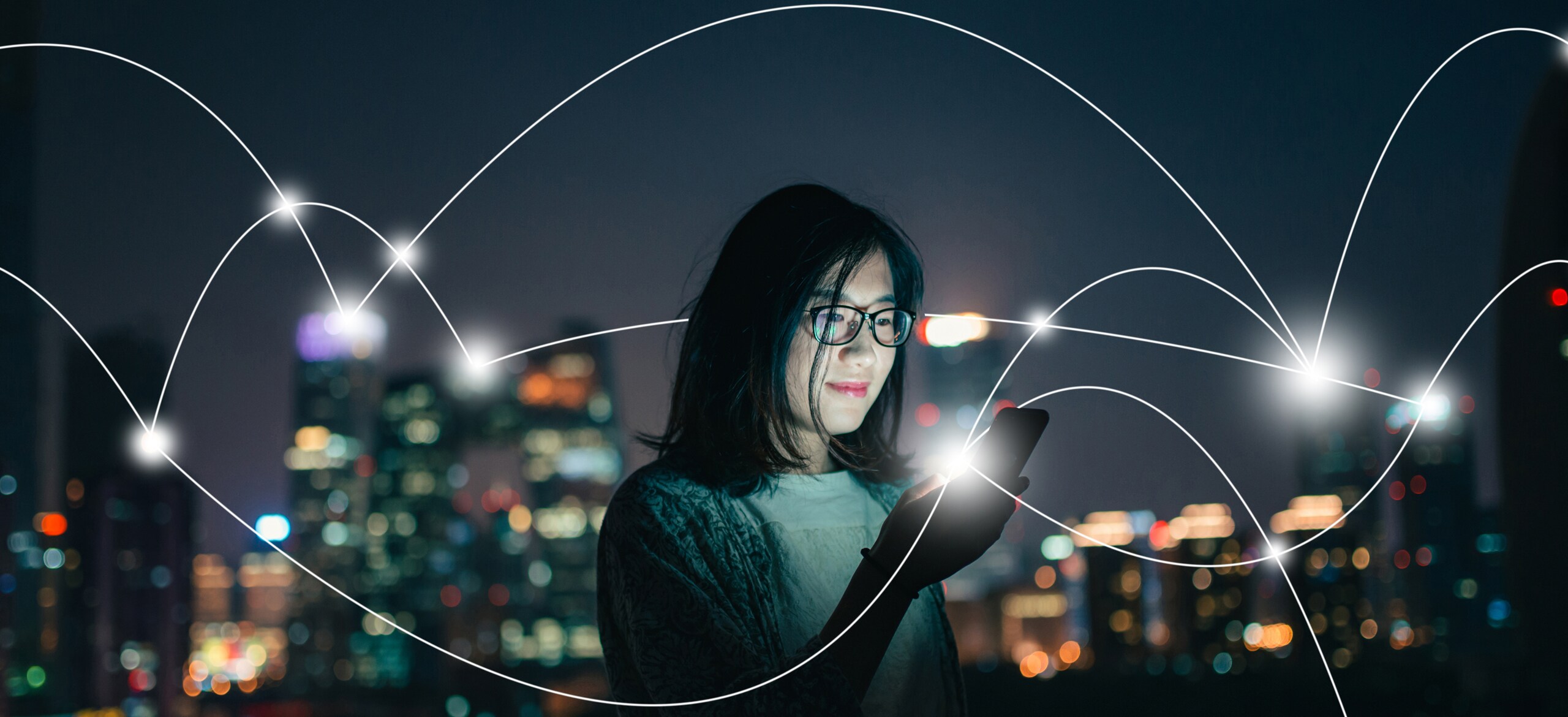 A woman looking at her phone with a nighttime city in the background and graphics depicting a IOT network