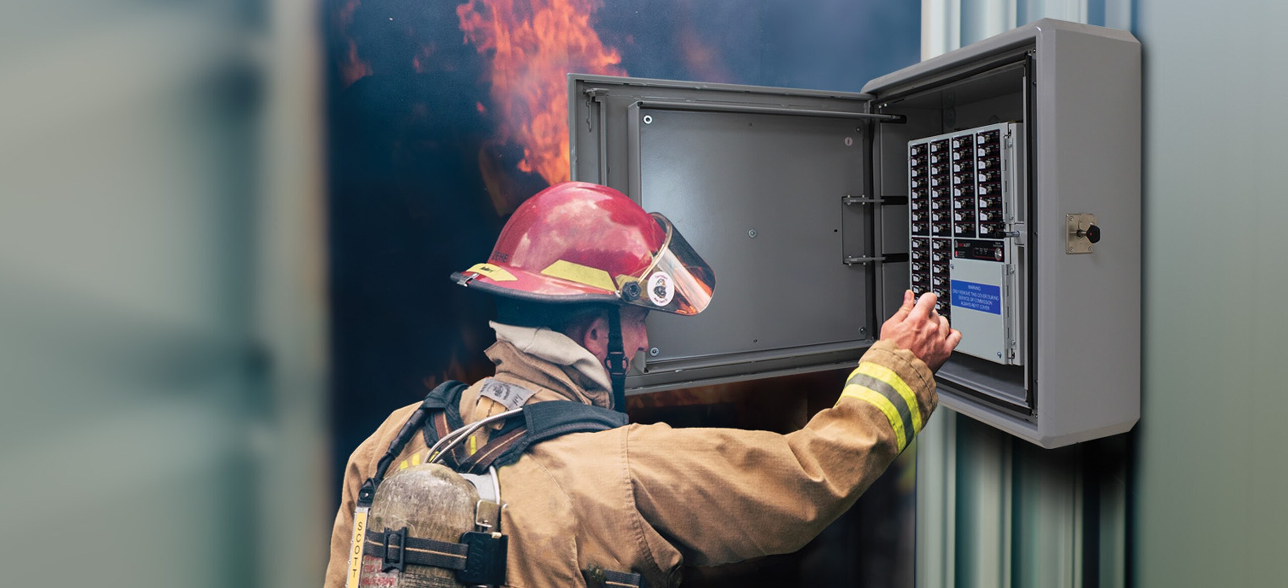 A fire-fighter handling an electric box with a fire in the background
