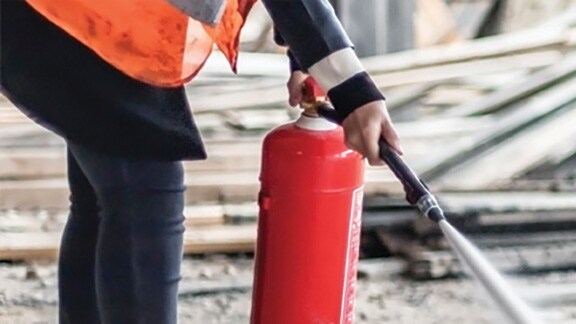 Close-up shot of a firefighter using a fire extinguisher