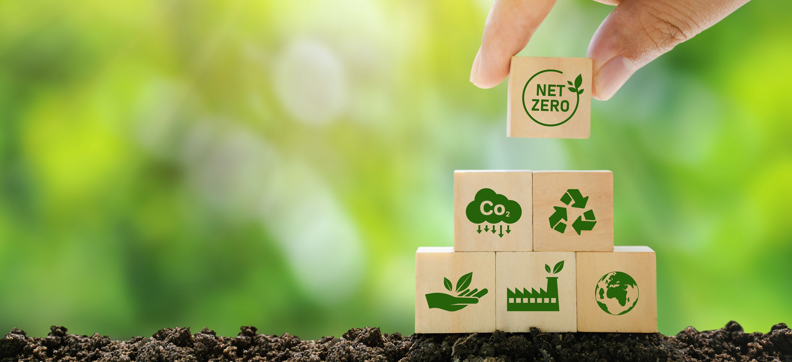Small wooden blocks with green sustainability icons stacked on the ground