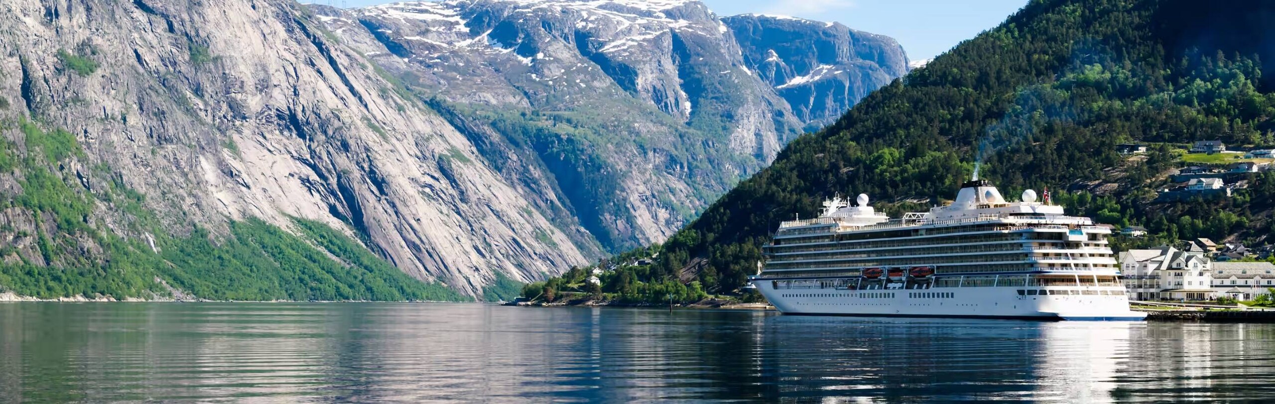 A ship sailing across a water body, surrounded by green hills