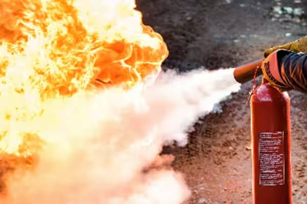 A fireman putting out a fire with a fire extinguisher.