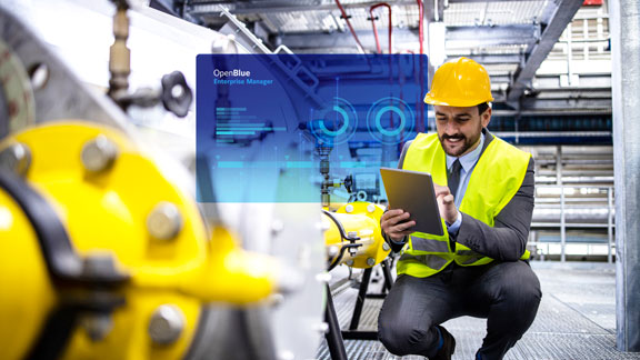 Refinery worker in a safety helmet and reflective vest working on a tab overlaid with graphic depicting Johnson Controls' OpenBlue Enterprise Manager