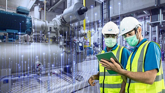 Two factory workers looking at a tablet in a factory