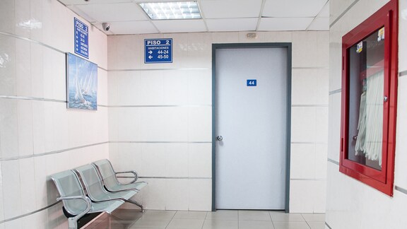 A surgeon in scrubs walking along a hospital passage