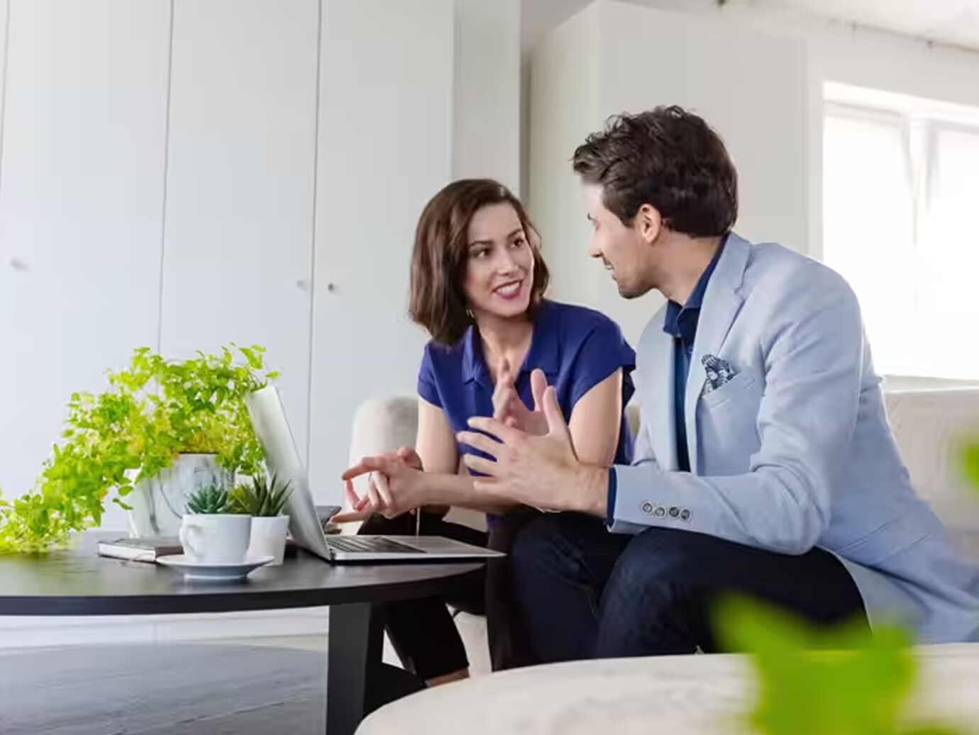 Man and woman sitting with a laptop and having a friendly conversation