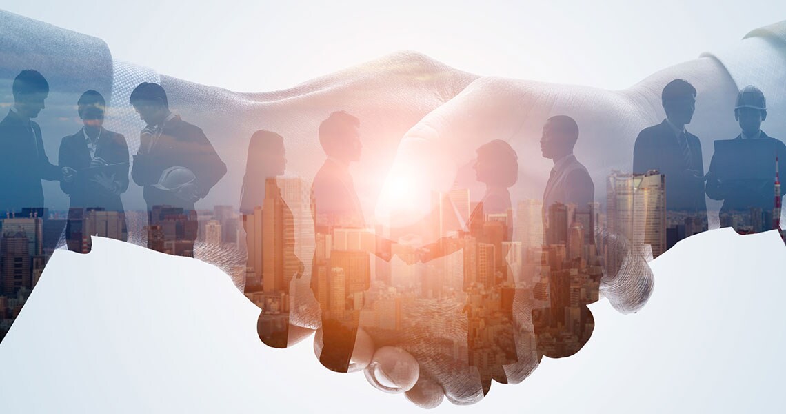 Silhouette of business people talking superimposed on an image of a hand-shake
