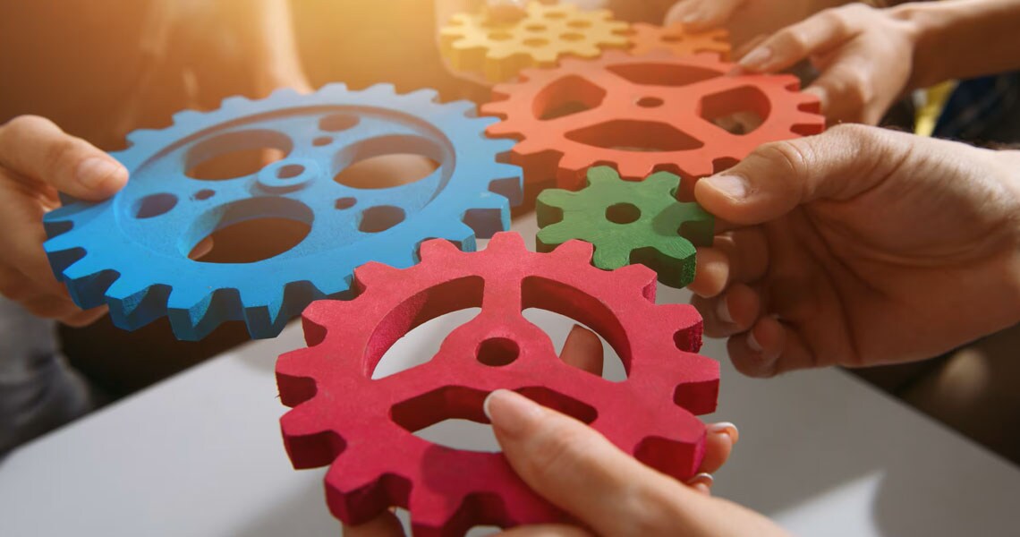 People holding colourful models of gears