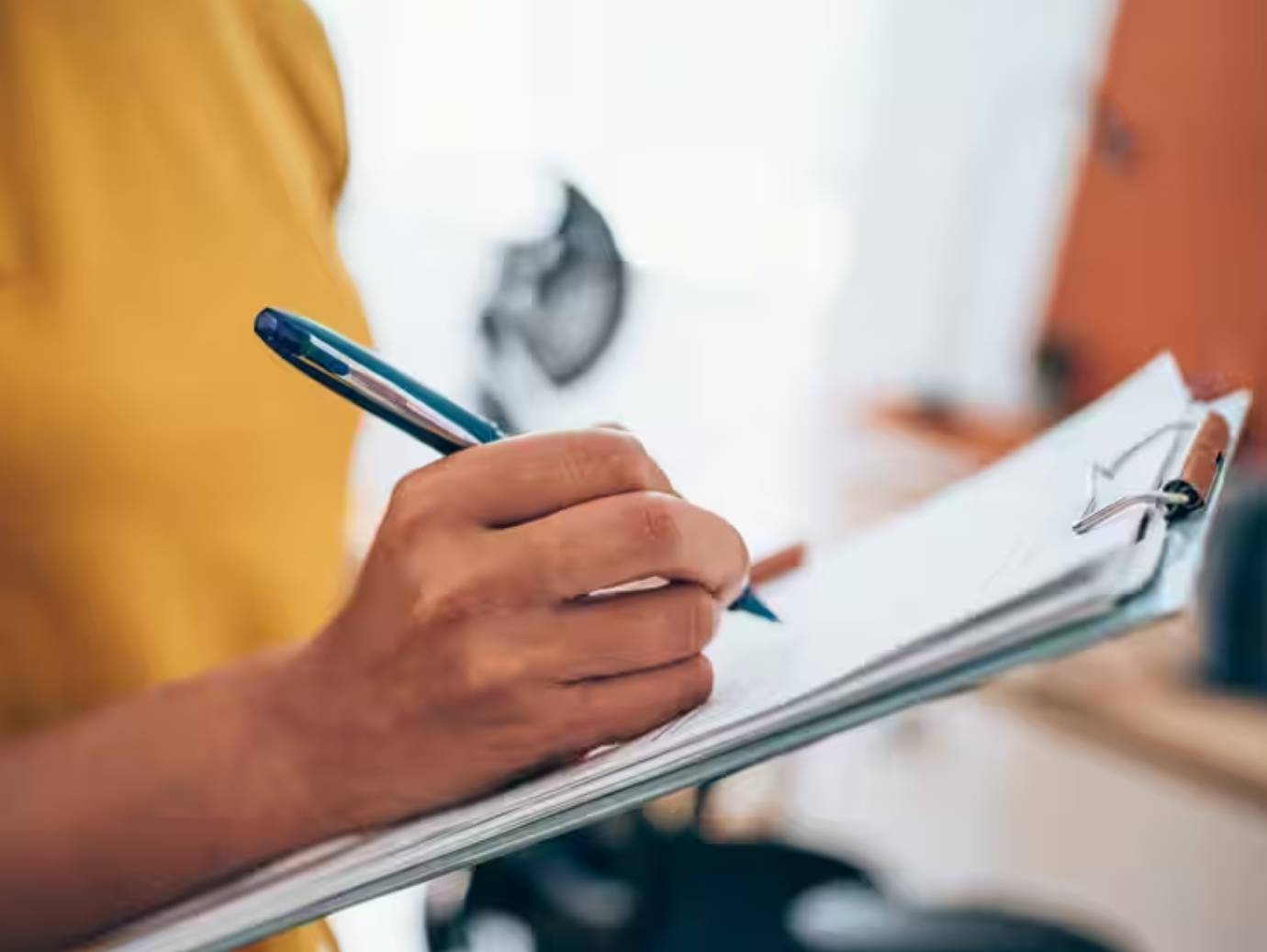 Close-up of a woman writing on a writing pad