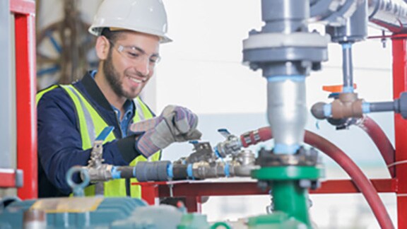 A mechanic smiling and fixing a machine