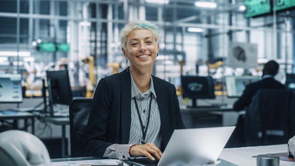 Lady smiling looking at camera while working on laptop