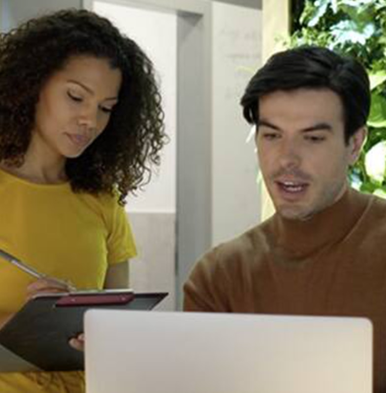 A man and woman focused on a laptop screen, engaged in a shared activity.