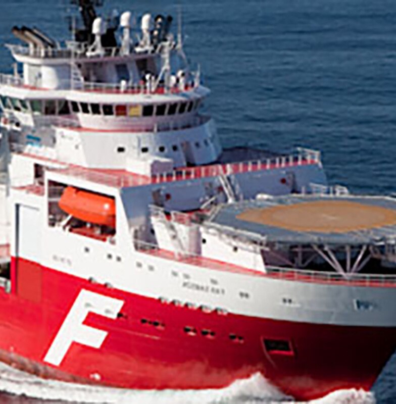 A red ship with a helipad sailing in the ocean