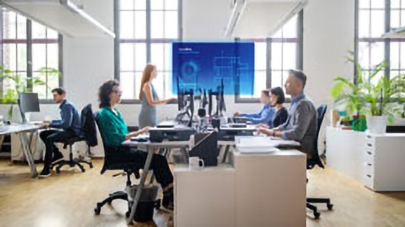 Employees sitting at a table watching a presentation with the OpenBlue Enterprise Manager overlaid on the screen